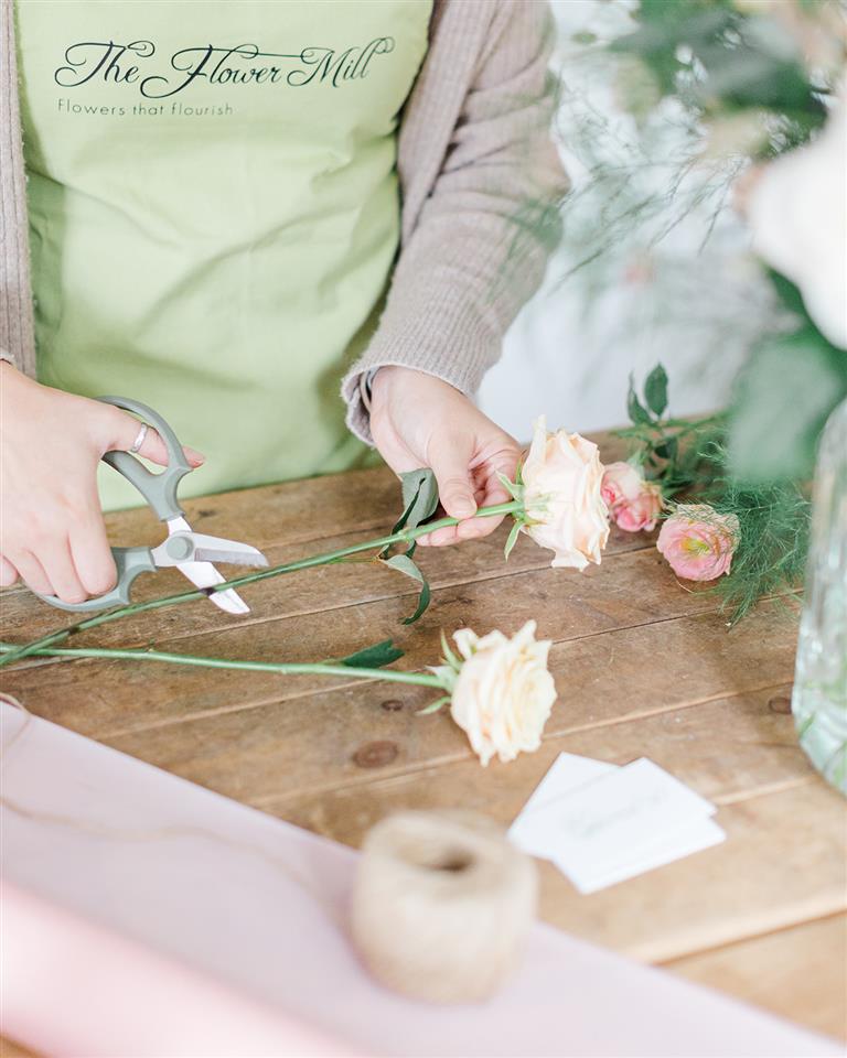 Top expert tip for extending the life of your flowers is to re cut the stems at a 45 degree angle like Kirsty is doing here. Cutting 2-3cm off at an angle give the flower a fresh boost of water and the angle means there is more surface area for the water to go up.